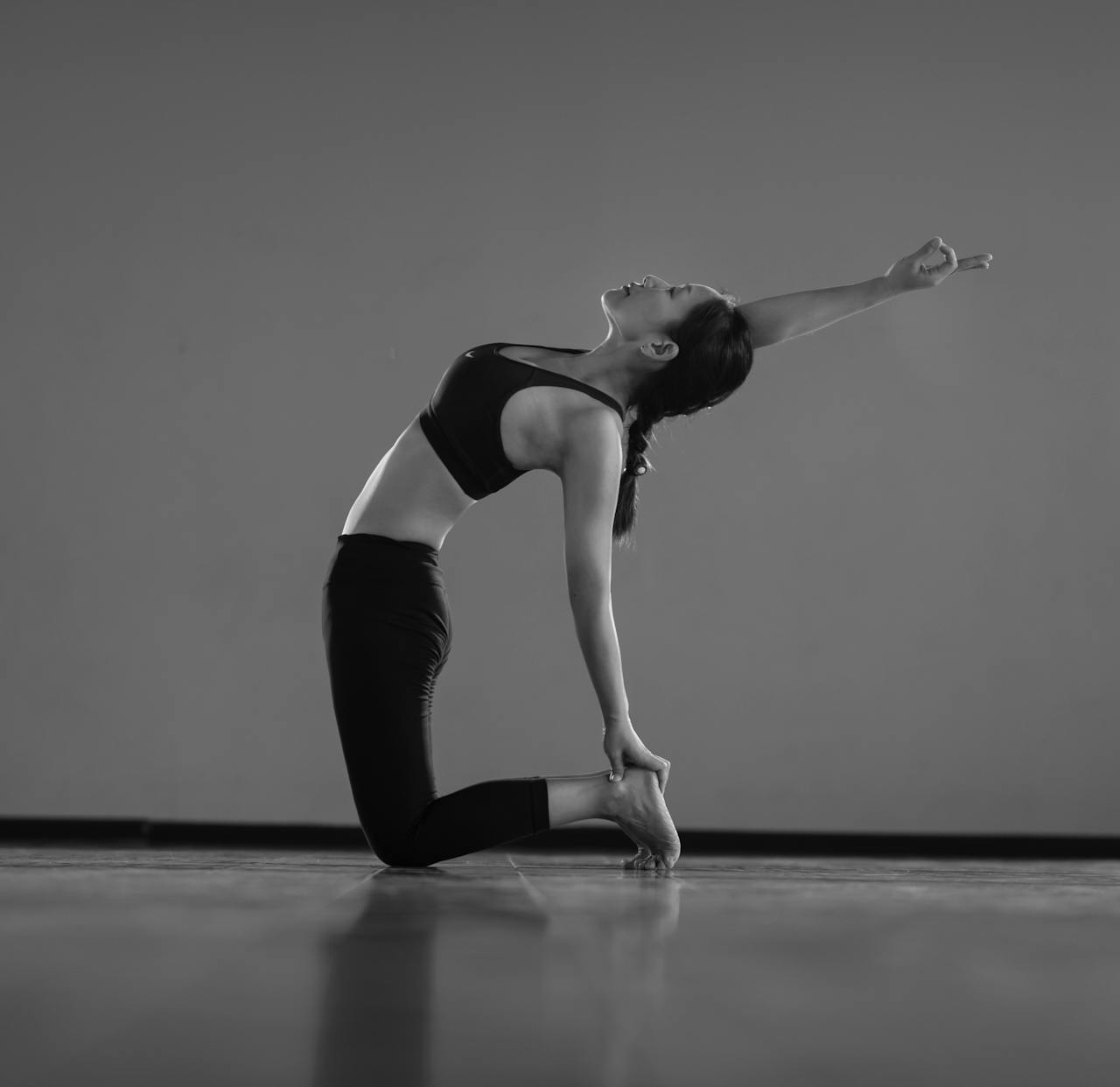 A woman gracefully performing a yoga pose indoors, showcasing balance and flexibility.